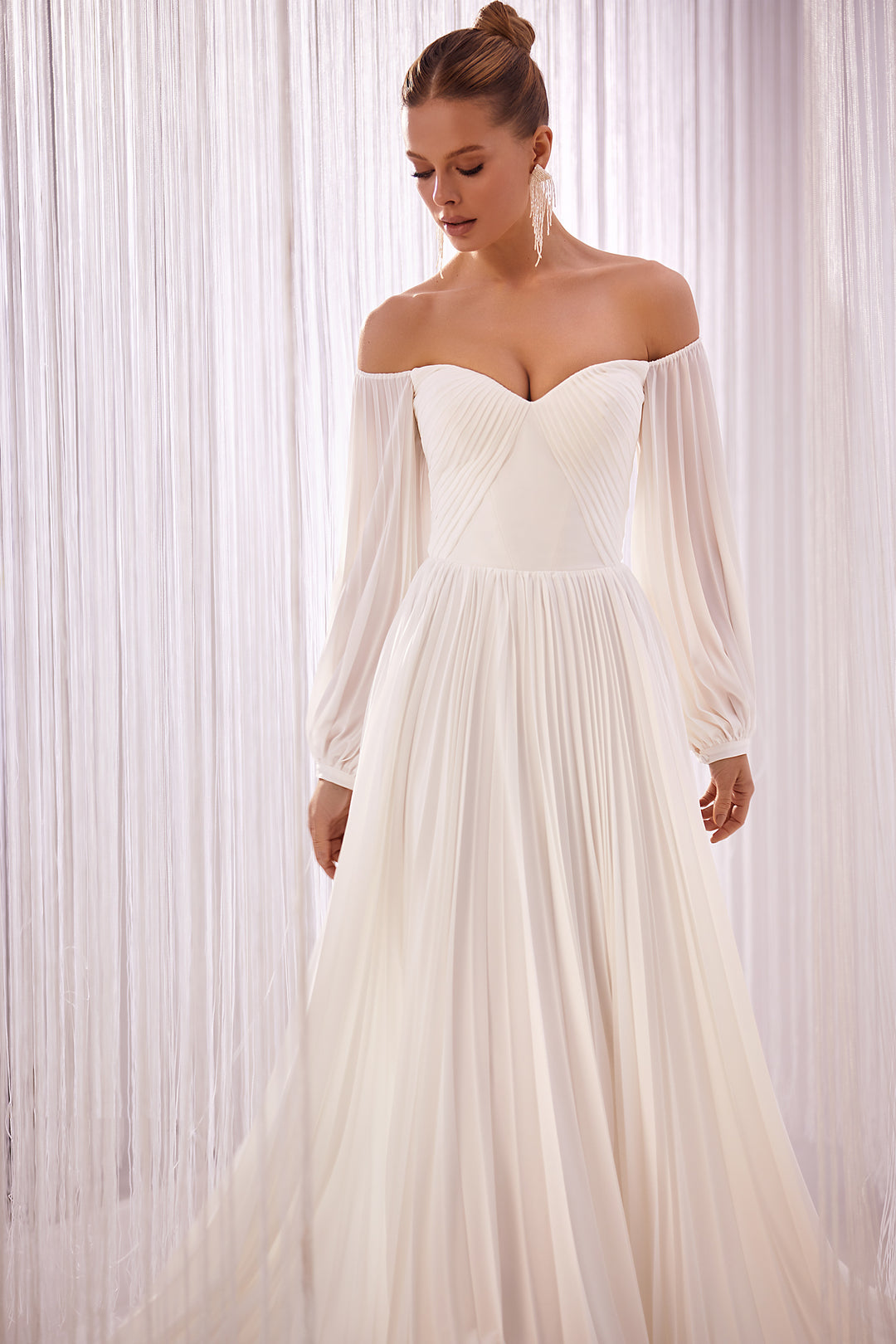 Woman in an off-the-shoulder chiffon pleated A-line wedding dress with sleeves. 