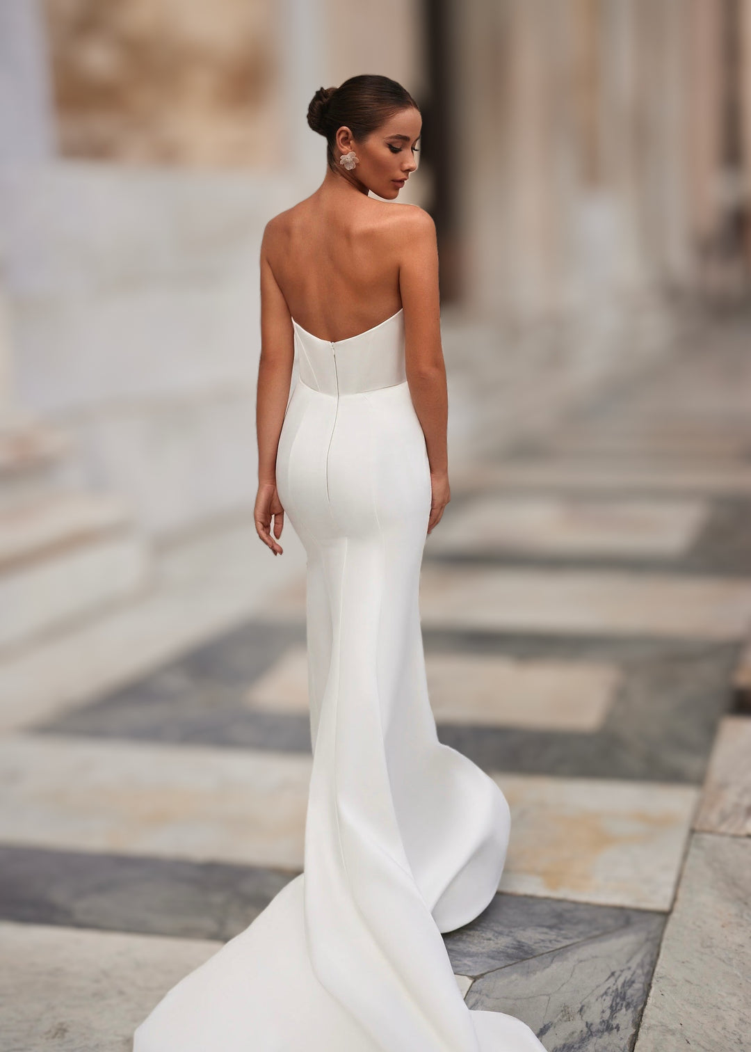 Woman wearing a strapless satin wedding dress with an open back  and train.