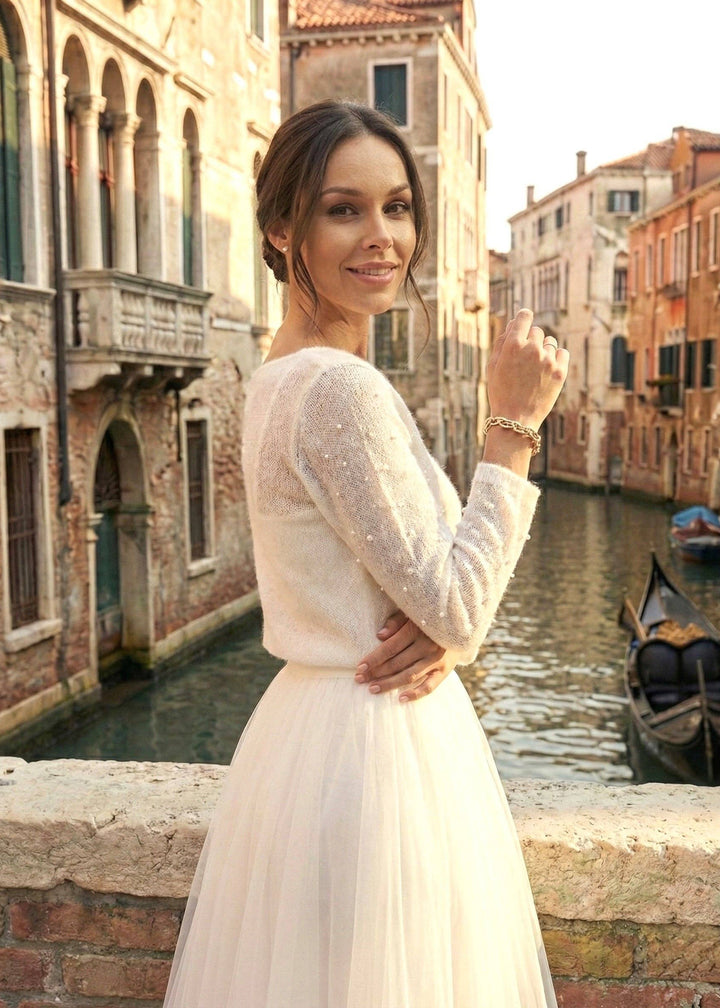 Woman in a white bridal dress standing by a canal with buildings in the background