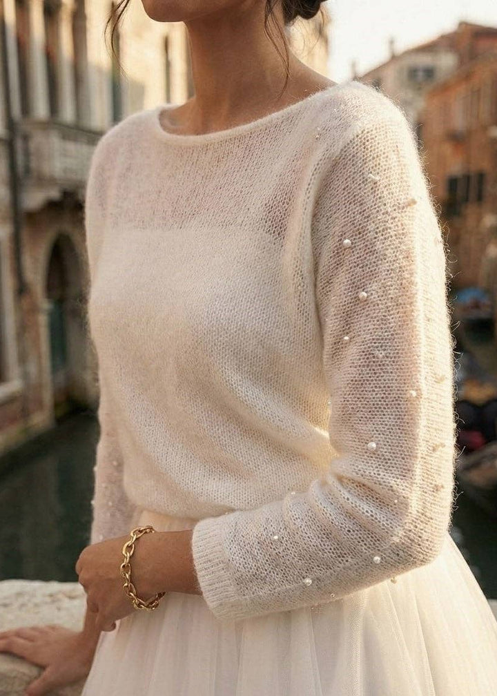 Woman wearing a white wool bridal cardigan with pearl embellishments in an urban setting.