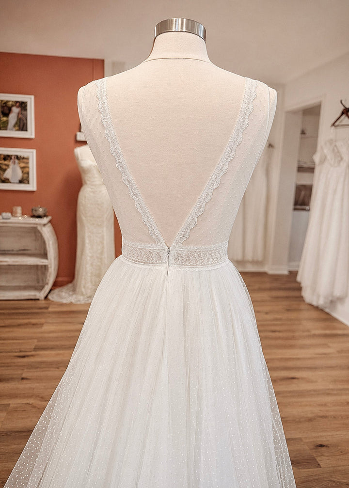 White boho wedding dress on a mannequin in a bridal store setting.