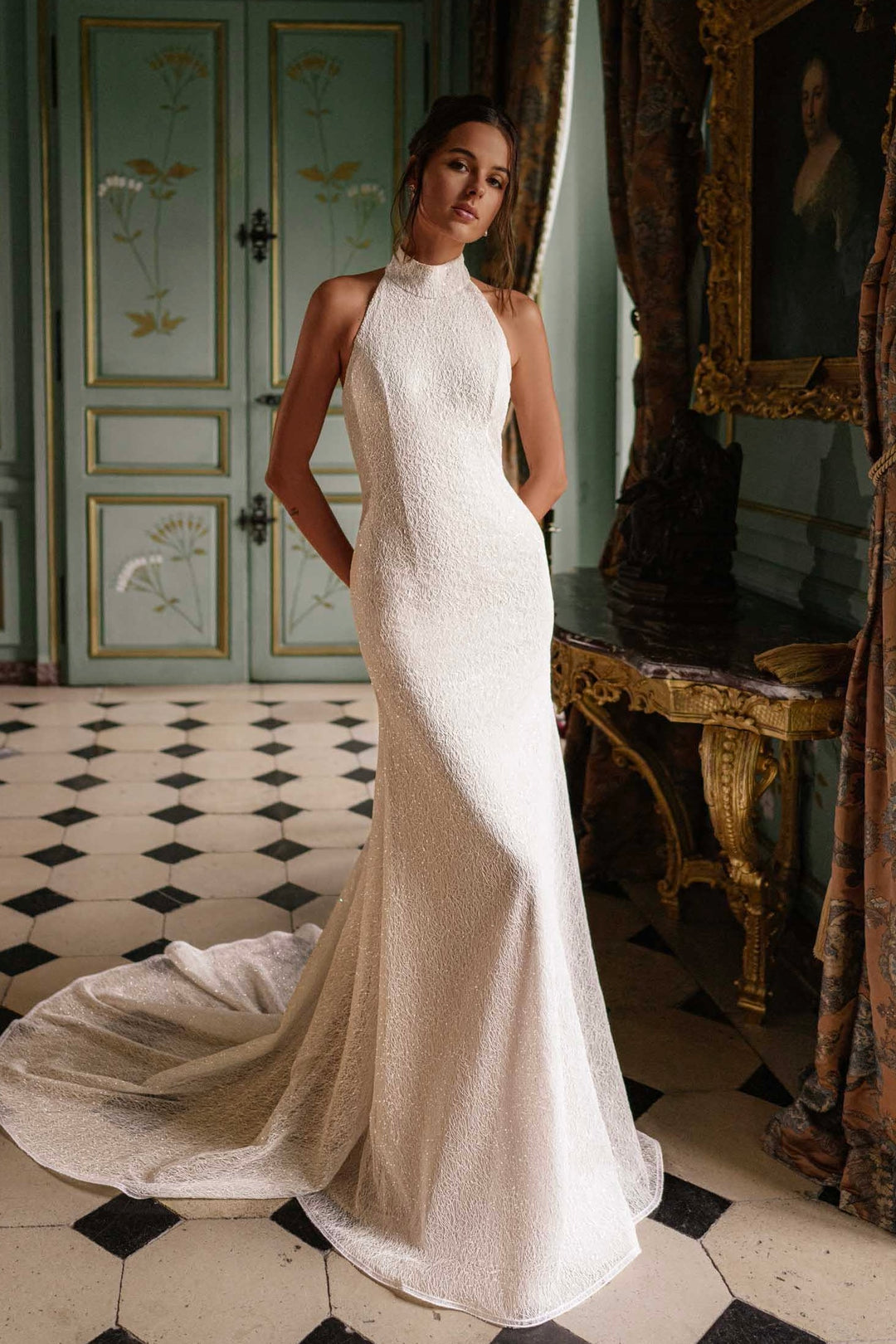Video of a woman wearing a fitted wedding dress with a train, standing in a room.